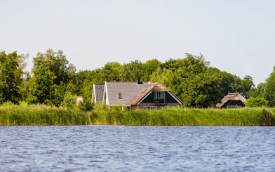 Traditional houses by the water in Giethoorn, surrounded by greenery, seen on a day trip from Amsterdam.