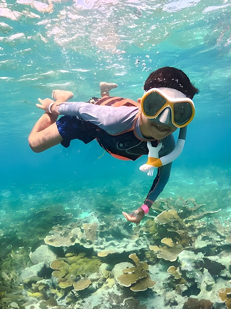 Snorkeler exploring coral reef during catamaran tour from Cancún to Isla Mujeres, Mexico.