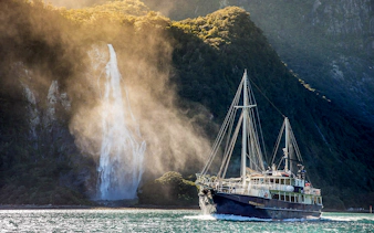 Cruise ship near waterfall in Doubtful Sound, New Zealand.