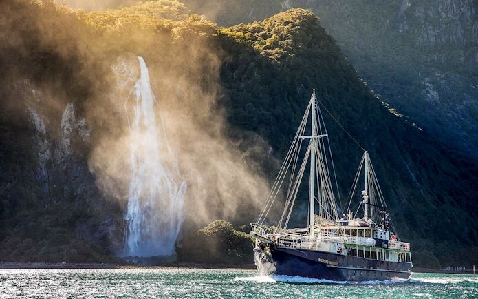 Cruise ship near waterfall in Doubtful Sound, New Zealand.
