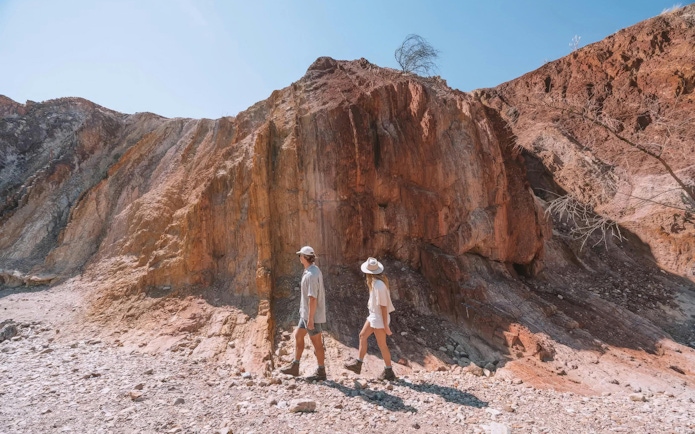 Two people walking near rocky cliffs in Uluru-Kata Tjuta, Australia.