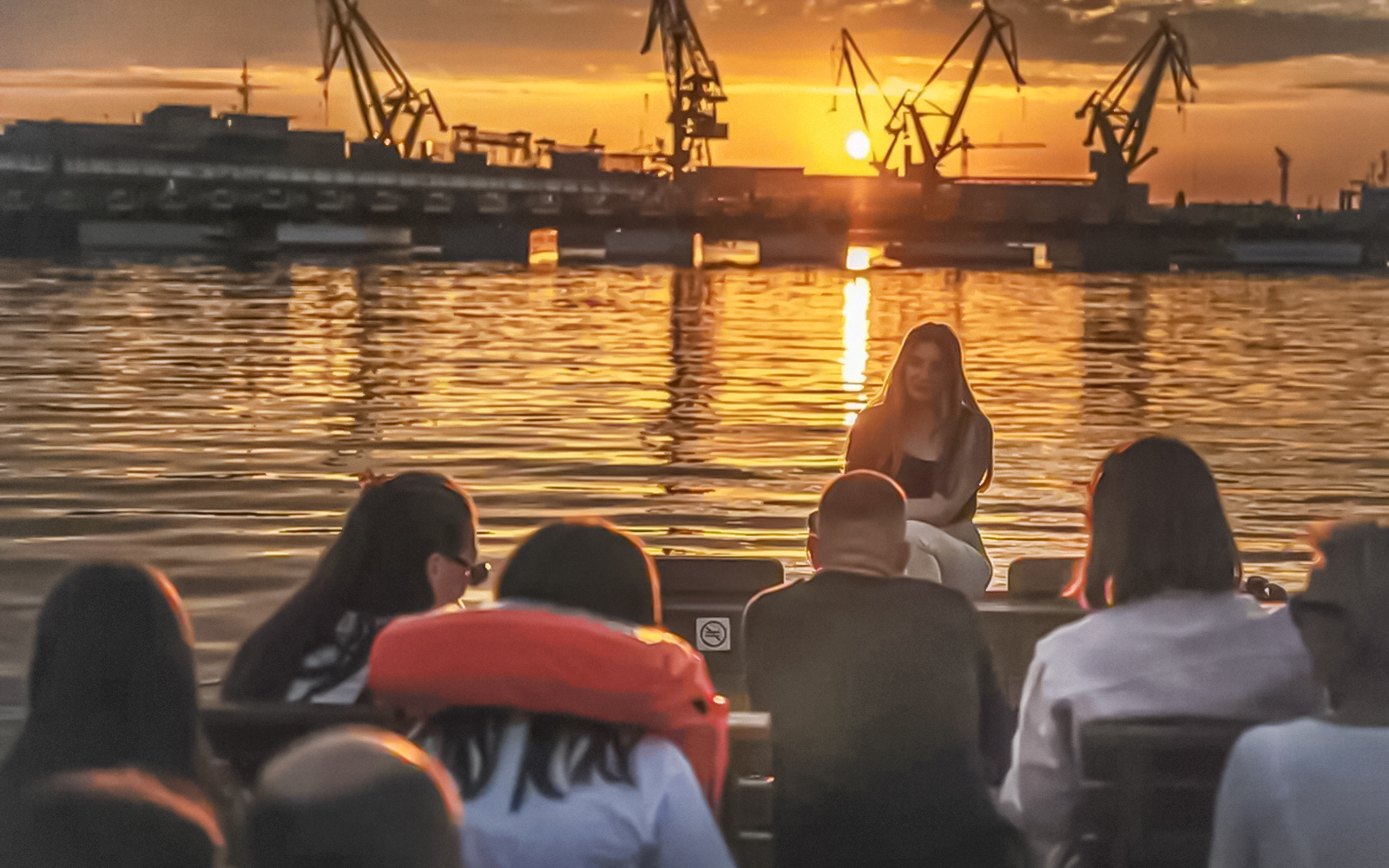Guests enjoying a sunset view of Gdansk Shipyard during a river cruise on a historical boat.