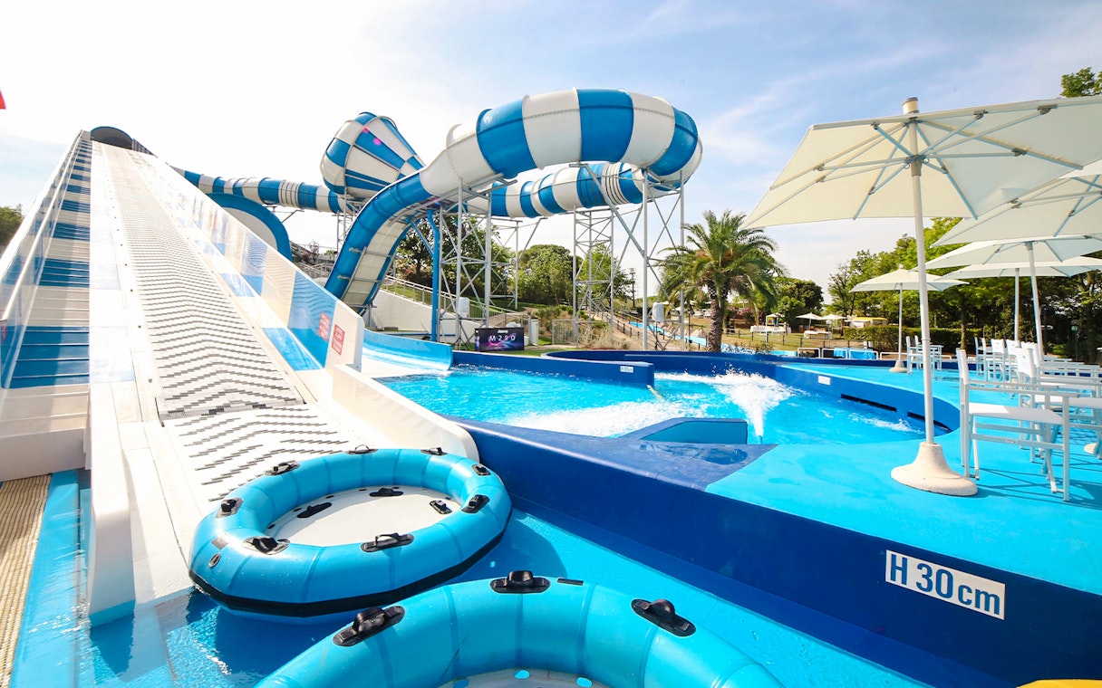 Water slides and pool area at Aquafan Water Park, featuring inflatable tubes and seating.