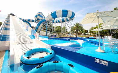 Water slides and pool area at Aquafan Water Park, featuring inflatable tubes and seating.