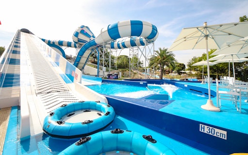 Water slides and pool area at Aquafan Water Park, featuring inflatable tubes and seating.