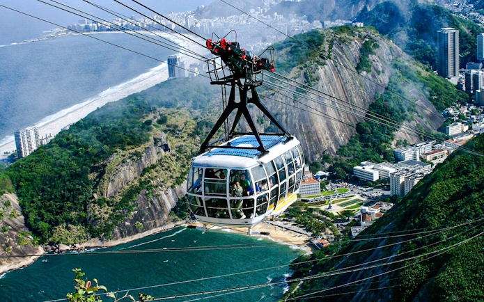 Sugarloaf Mountain cable car moving over Rio de Janeiro coastline.