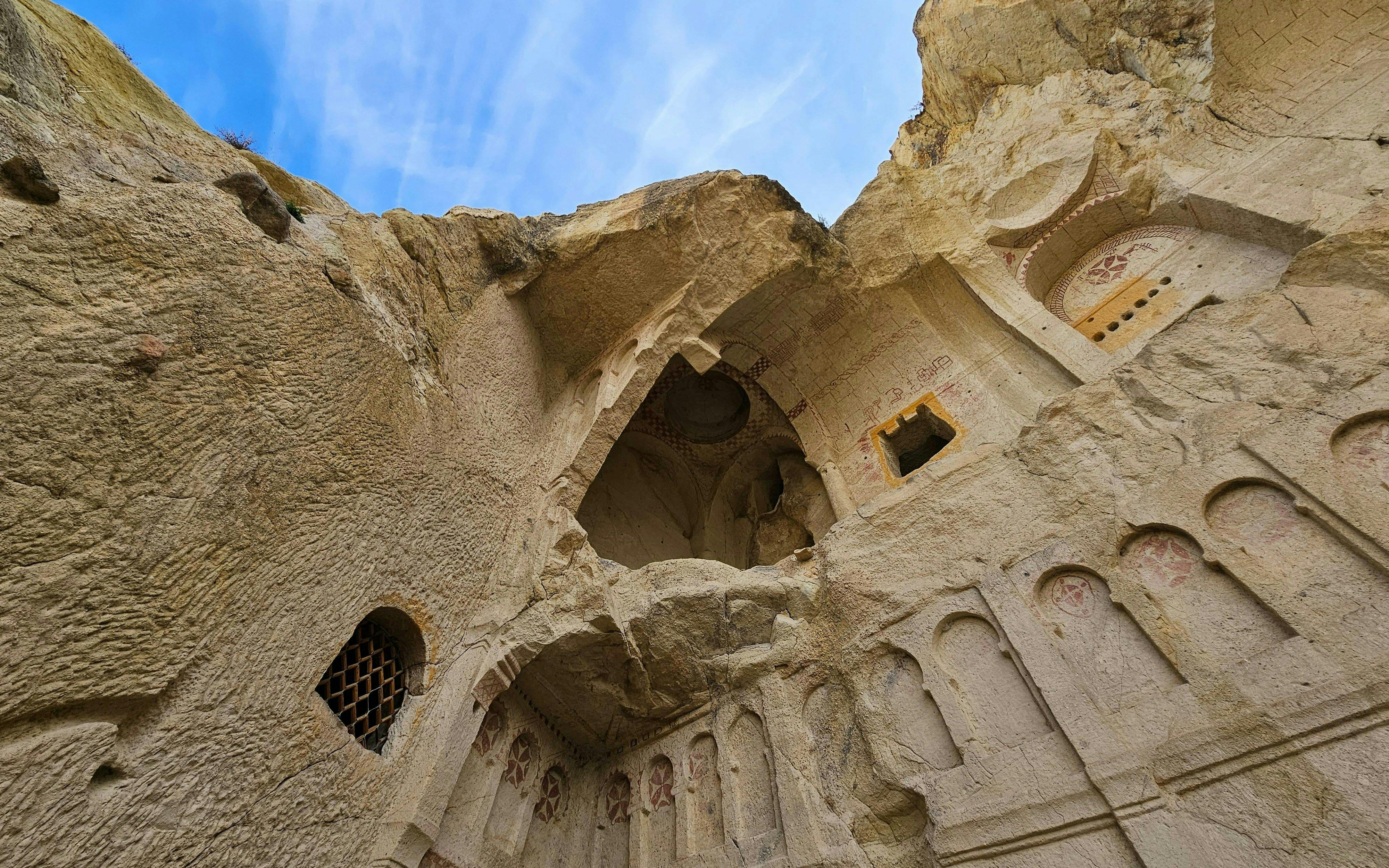 Ancient rock-cut church interior in Goreme National Park, Turkey, with carved arches and frescoes.