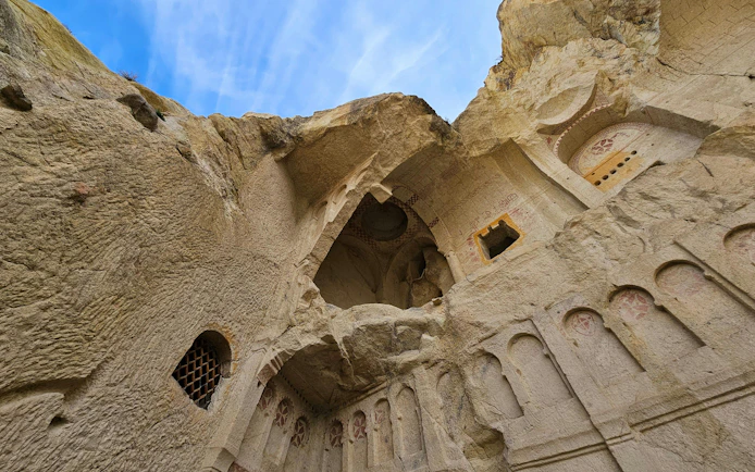 Ancient rock-cut church interior in Goreme National Park, Turkey, with carved arches and frescoes.