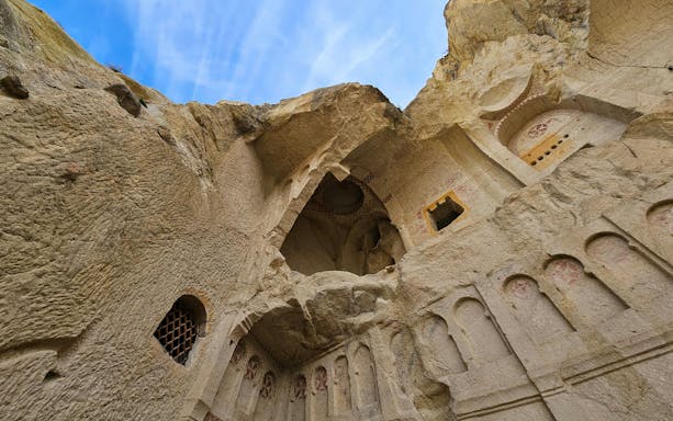 Ancient rock-cut church interior in Goreme National Park, Turkey, with carved arches and frescoes.