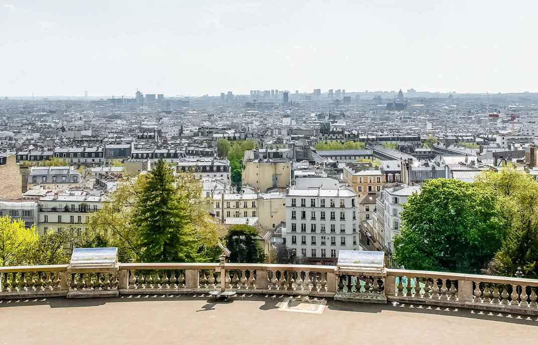 View of Paris skyline from Montmartre, featuring cityscape and greenery.