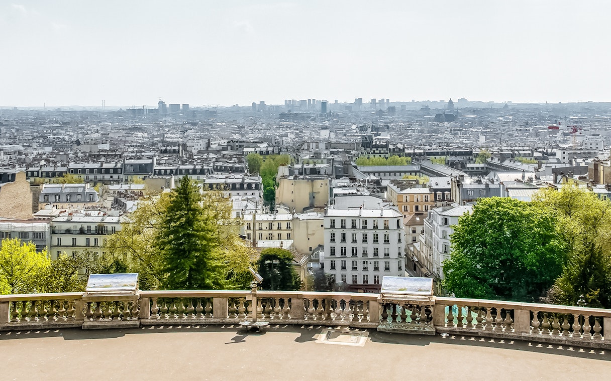 View of Paris skyline from Montmartre, featuring cityscape and greenery.