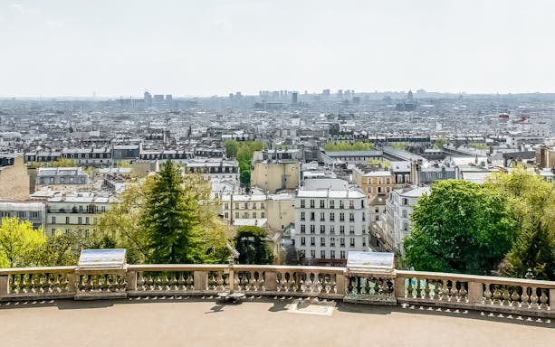 View of Paris skyline from Montmartre, featuring cityscape and greenery.