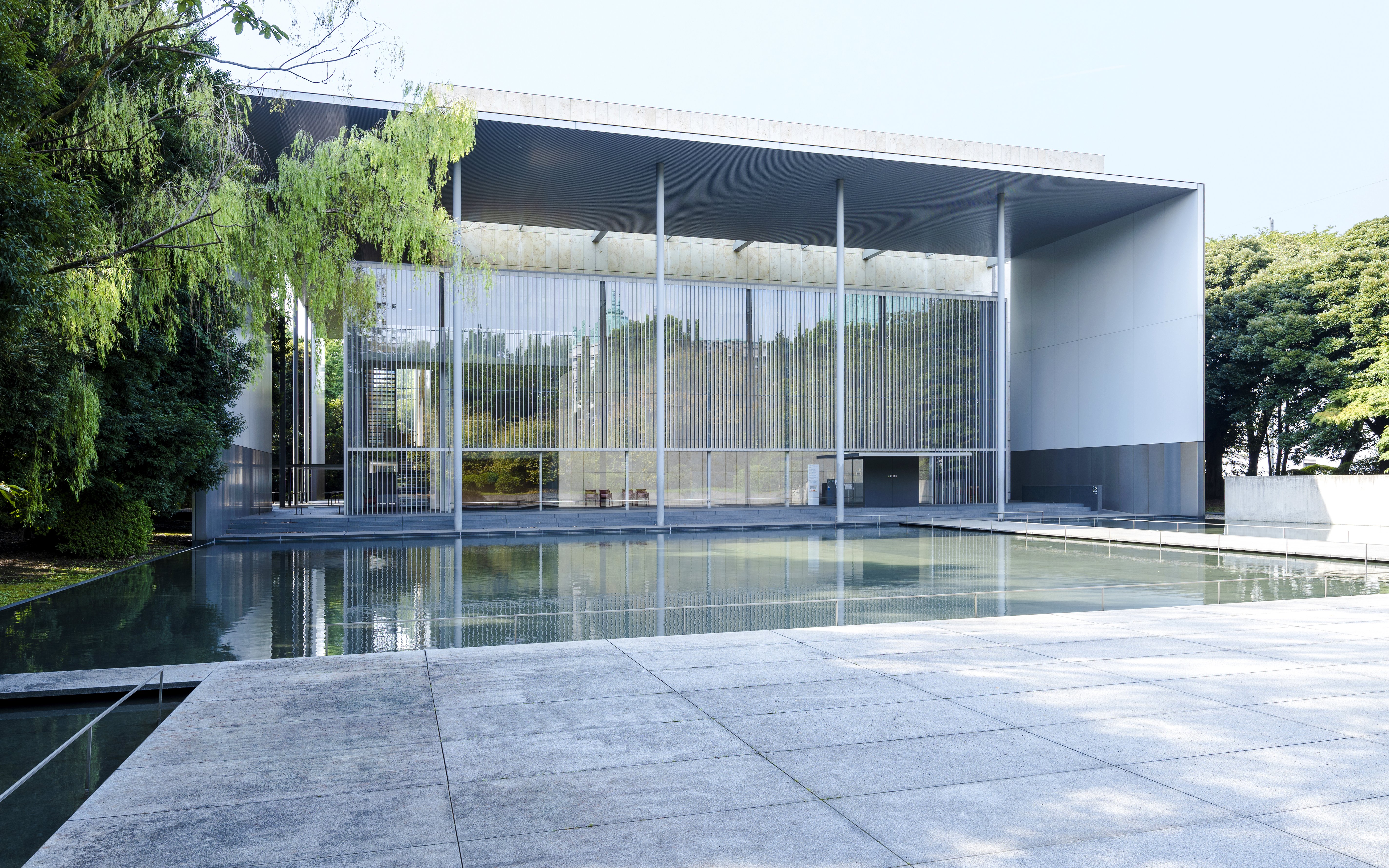 Modern building with glass facade and reflecting pool at Tokyo National Museum.