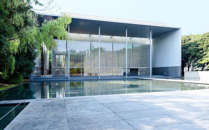 Modern building with glass facade and reflecting pool at Tokyo National Museum.