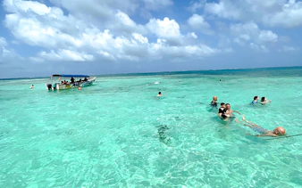 Boat and swimmers in clear waters of Islas de San Blas, Panama.