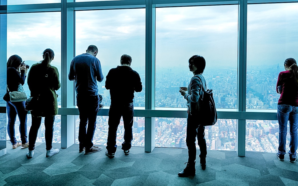 Visitors enjoying the view from Taipei 101 Observatory, overlooking Taipei city.