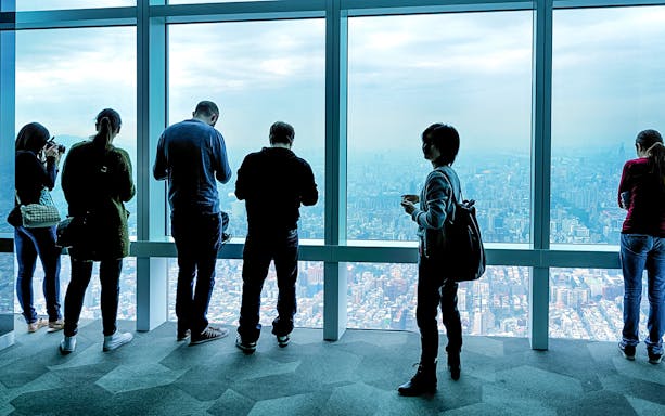 Visitors enjoying the view from Taipei 101 Observatory, overlooking Taipei city.