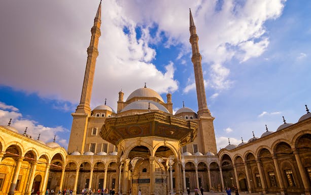 Citadel of Cairo with mosque domes and minarets under a blue sky.