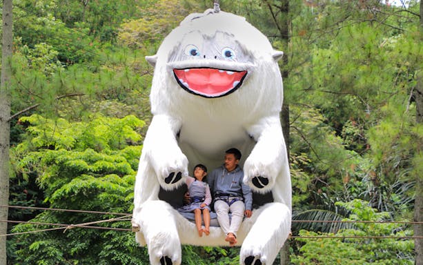 Visitors sitting in a large white creature ride at Dago Dreampark, surrounded by lush greenery.