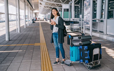 Traveler with luggage at Tirana Airport bus terminal for Durres transfer.