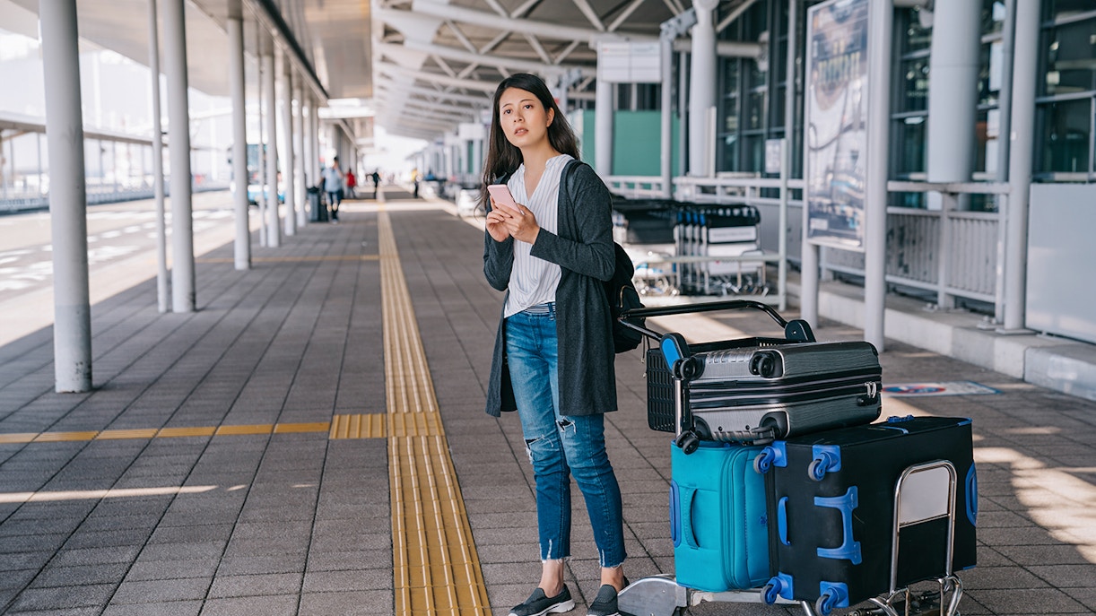 Traveler with luggage at Tirana Airport bus terminal for Durres transfer.