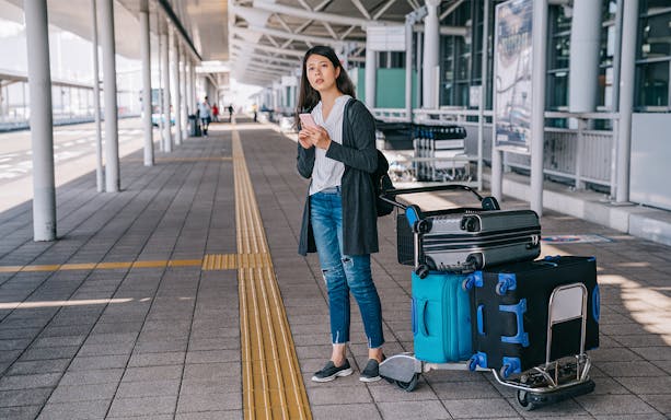 Traveler with luggage at Tirana Airport bus terminal for Durres transfer.