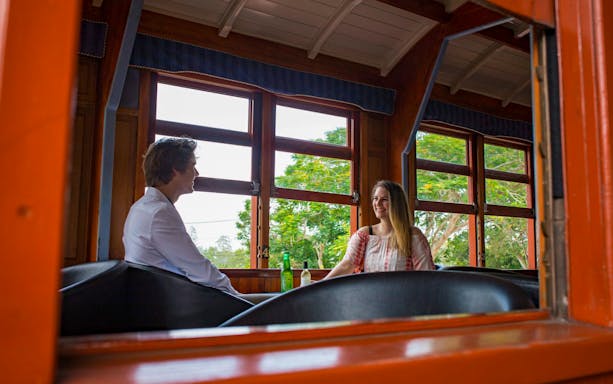 Couple enjoying VIP Club Car on Mary Valley Rattler Train with scenic views.
