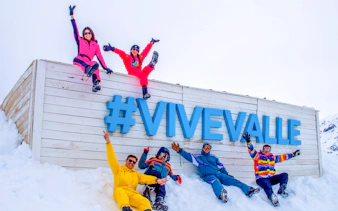 Group enjoying snow at Valle Nevado with #ViveValle sign, Santiago tour.