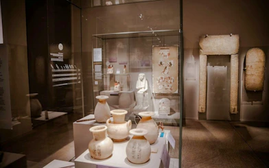 Artifacts and statues displayed in a glass case at the Egyptian Museum in Turin.