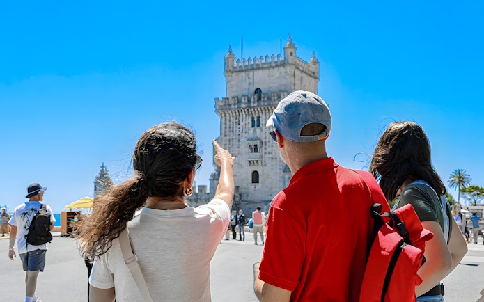 Tour guide pointing at Belem Tower with tourists in Lisbon.