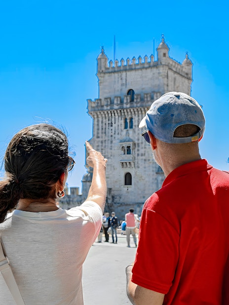 Tour guide pointing at Belem Tower with tourists in Lisbon.
