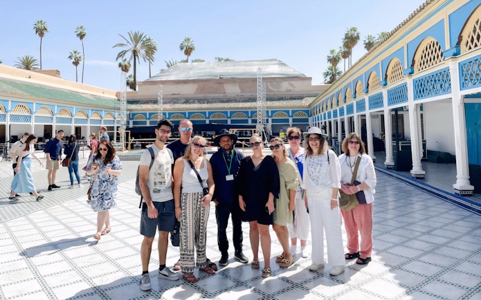 Tour group with guide at Bahia Palace courtyard in Marrakech.