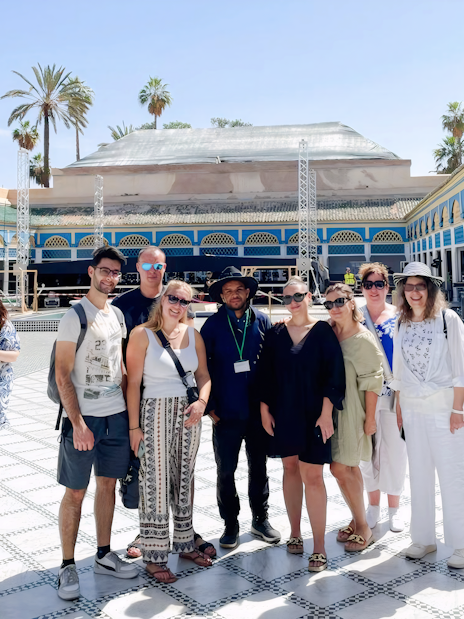 Tour group with guide at Bahia Palace courtyard in Marrakech.