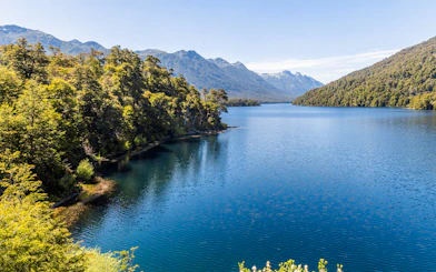 Patagonian lake with clear water, surrounded by forests and mountain peaks.