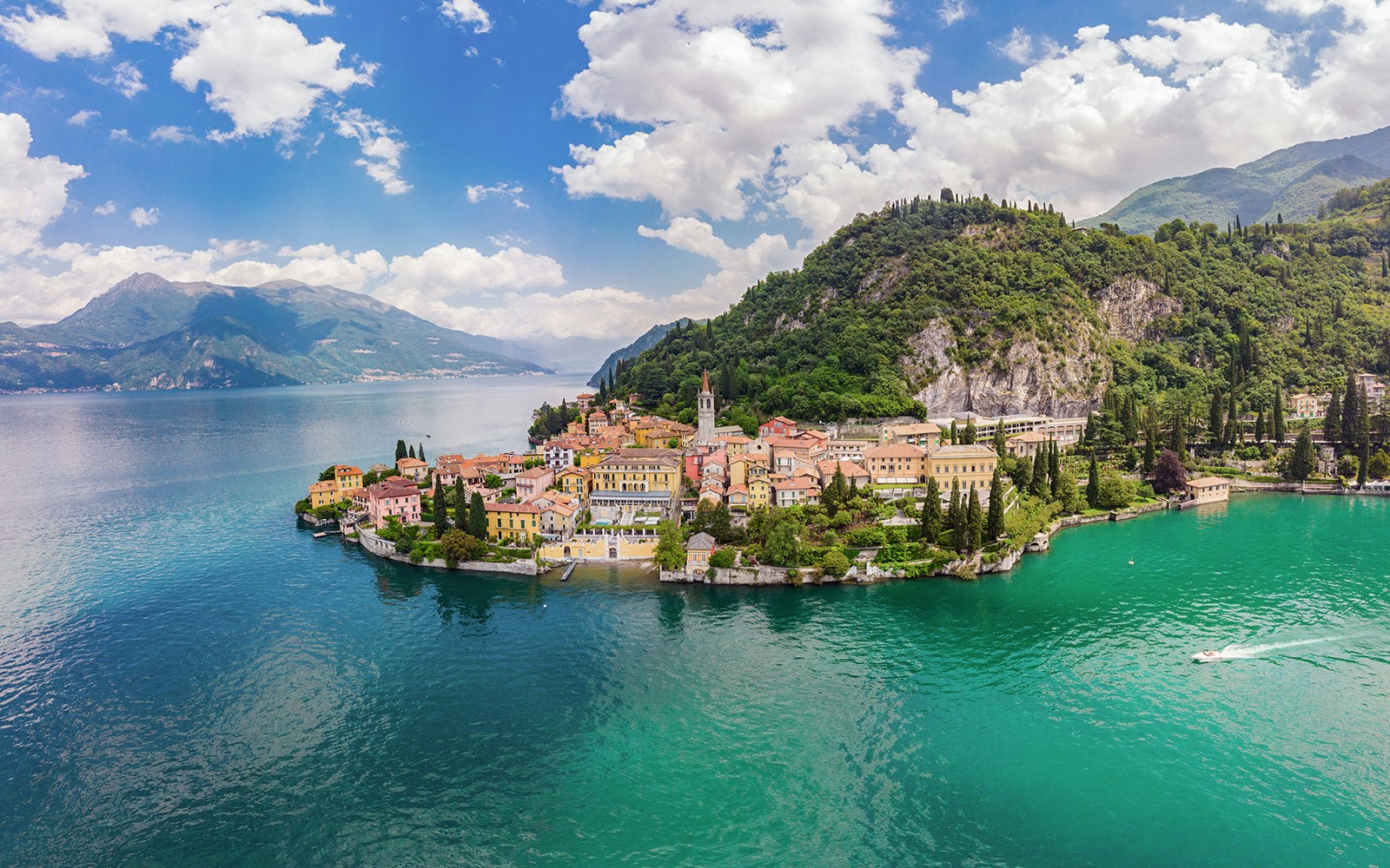 Panoramic view of Lake Como with colorful village and lush hills.