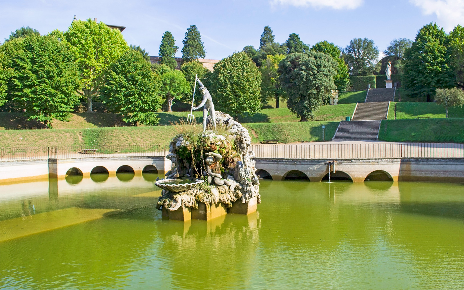 Fountain of Neptune in Boboli Gardens, Florence, surrounded by greenery and water.
