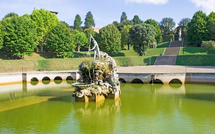 Fountain of Neptune in Boboli Gardens, Florence, surrounded by greenery and water.