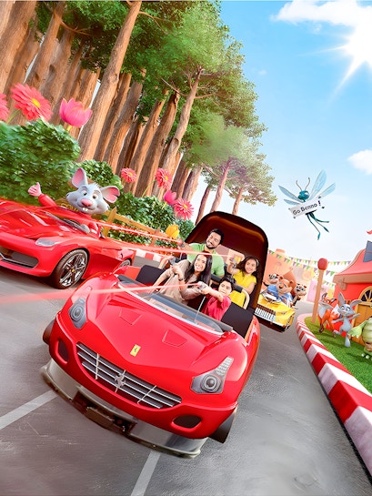 Family enjoying a ride in a red car at Ferrari World Theme Park, surrounded by animated characters.