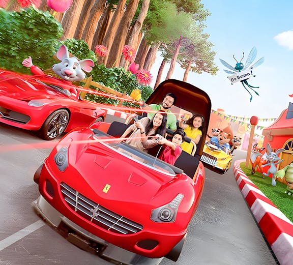 Family enjoying a ride in a red car at Ferrari World Theme Park, surrounded by animated characters.