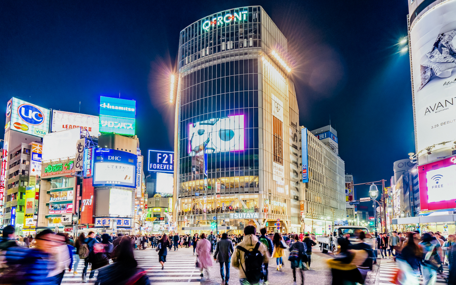 Shibuya Crossing at night with tourists and bright billboards, Tokyo, Japan.