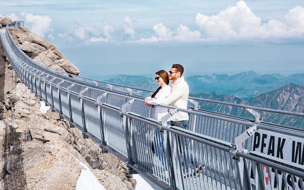 Couple on Glacier 3000 suspension bridge with mountain views, Geneva.
