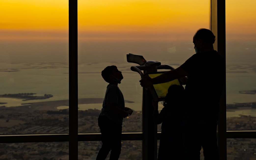 Visitors enjoying sunrise view from Burj Khalifa Level 124 observation deck.