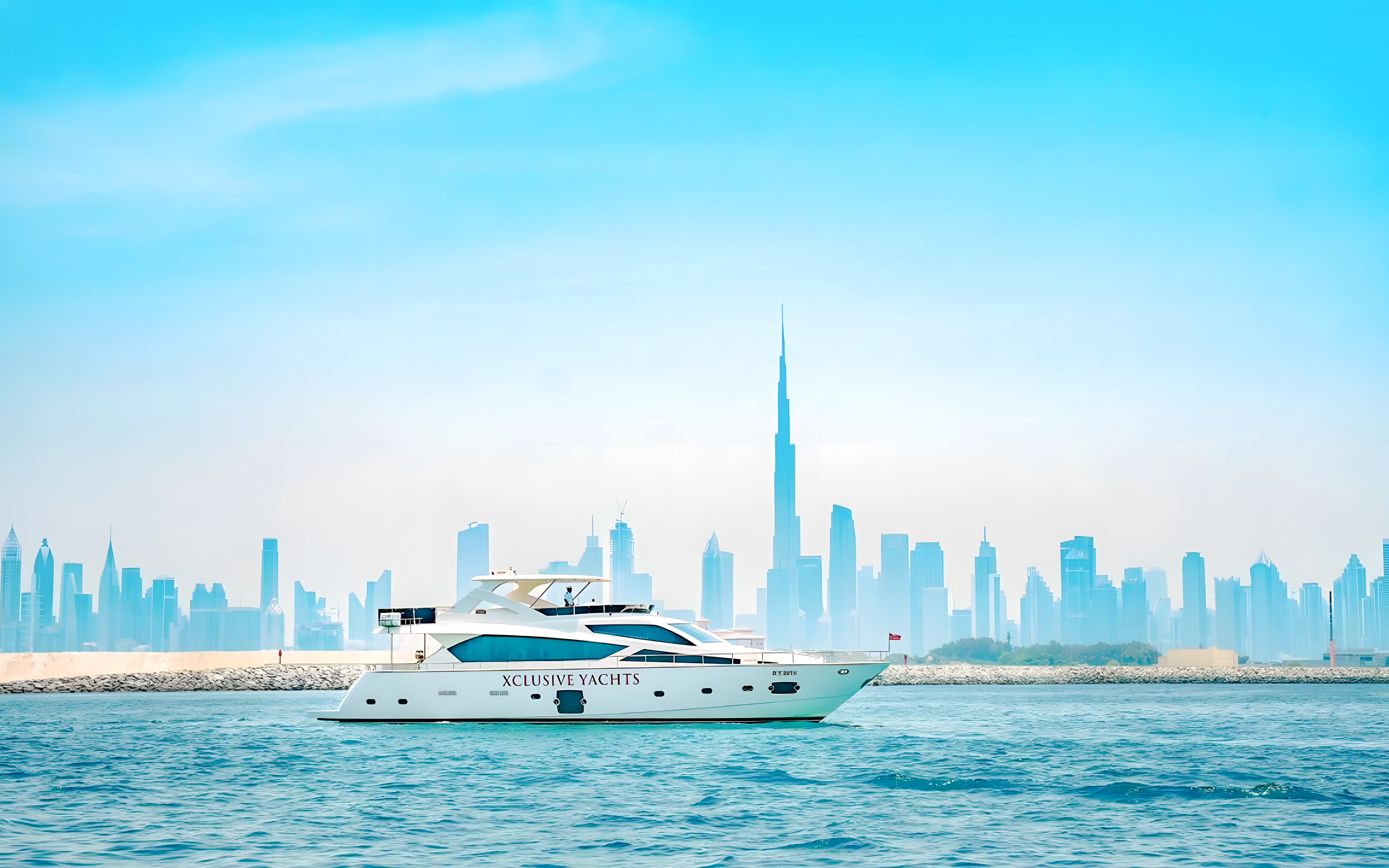 Yacht sailing through canal with Burj Khalifa and Dubai skyline in background.