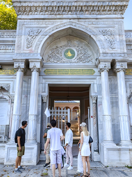 Visitors at the entrance of Topkapi Palace, Istanbul, exploring historic architecture.