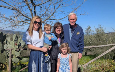 Family enjoying Tuscan farm tour with scenic views and olive trees in San Gimignano.