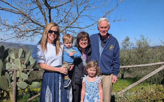 Family enjoying Tuscan farm tour with scenic views and olive trees in San Gimignano.