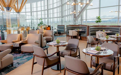 Plaza Premium First lounge seating area at Vancouver International Airport, featuring modern decor and dining tables.