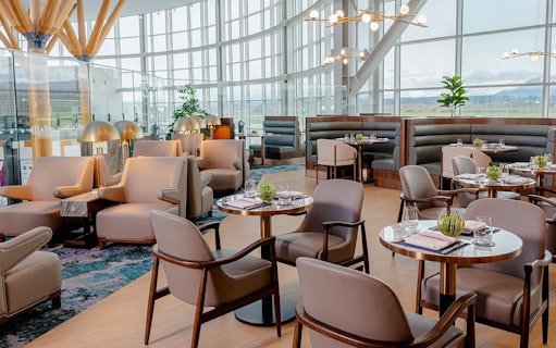 Plaza Premium First lounge seating area at Vancouver International Airport, featuring modern decor and dining tables.