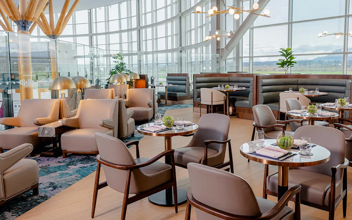 Plaza Premium First lounge seating area at Vancouver International Airport, featuring modern decor and dining tables.