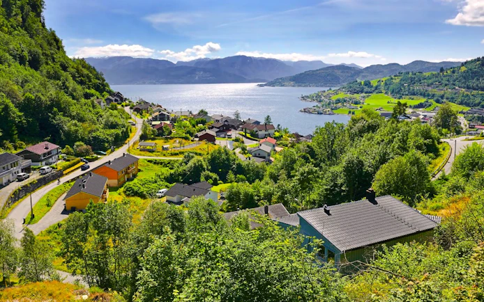 View of Hardangerfjord in Norway with houses and lush greenery.
